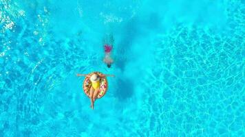 Top view of a couple having fun in the pool, the man swims and the woman lies on an inflatable donut video