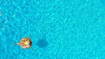 Aerial view of a woman in yellow swimsuit lying on a donut in the pool video