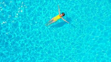 aereo Visualizza di un' donna nel giallo costume da bagno nuoto nel il piscina. estate stile di vita video