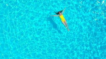 aereo Visualizza di un' donna nel giallo costume da bagno nuoto nel il piscina. estate stile di vita video