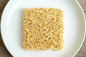 Instant noodles on white plate on brown wooden table photo