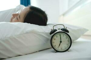alarma reloj ese es yendo a anillo a Siete en Mañana en antecedentes de mujer dormido en cama. foto