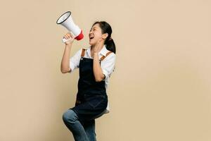 Shout out loud with megaphone. Asian female employees wearing apron announces with a voice about promotions and advertisements for products at a discounted price. photo