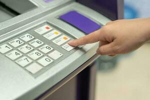 Close up female hand pushing passwords bank on the pin button of ATM machine to withdraw money photo