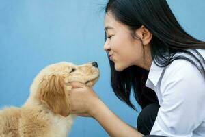 Closeup portrait of beautiful Asian woman kissing her best friend dog on blue background. photo