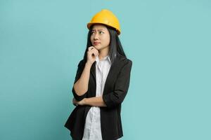 Portrait of Asian female engineer with yellow helmet on green background She made some curious gestures, looking up. photo