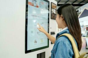 Asian female tourist choosing coffee menu from vending machine photo