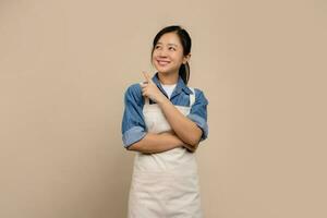 Cheerful smiling asian female barista wear cream color apron, She is pointing and looking upper left corner joyful, showing promo photo