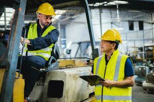 almacén trabajador hablando con máquina elevadora operador en fábrica foto