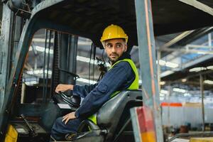 worker wearing helmet with driving forklift backwards in warehouse photo