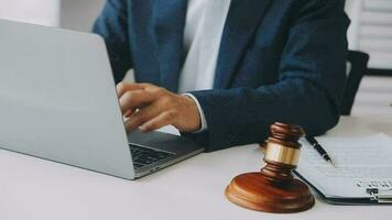 Justice and law concept.Male judge in a courtroom with the gavel, working with, computer and docking keyboard, eyeglasses, on table in morning light video