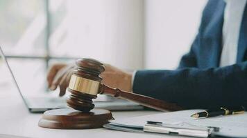 Justice and law concept.Male judge in a courtroom with the gavel, working with, computer and docking keyboard, eyeglasses, on table in morning light video