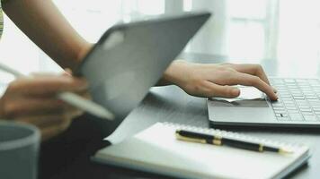 el retrato de una joven mujer asiática independiente está trabajando en su trabajo en una tableta de computadora en una oficina moderna. hacer un informe de análisis contable datos de inversión inmobiliaria, concepto de sistemas financieros y fiscales. video