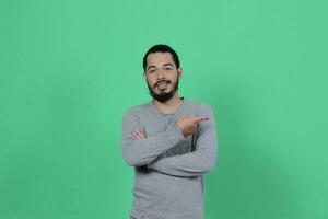 bearded asian man poses wearing a gray shirt against a green background photo