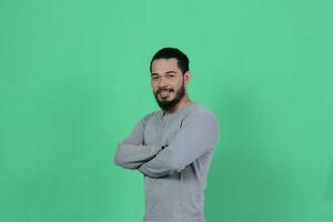 barbado asiático hombre poses vistiendo un gris camisa en contra un verde antecedentes foto