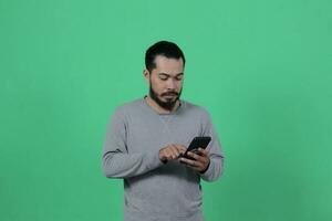 asiático hombre expresión mientras utilizando teléfono inteligente foto