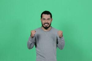 bearded asian man poses wearing a gray shirt against a green background photo