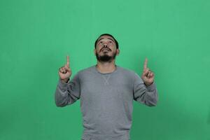 bearded asian man poses wearing a gray shirt against a green background photo