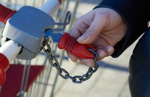 woman hand key into the lock grocery cart. photo