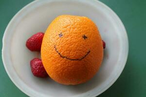 Smiling orange on a green background photo