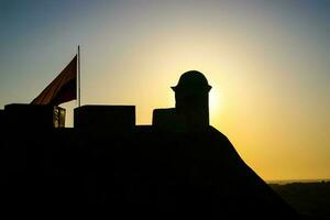 Silhouette of the historical San Felipe Castle and the Colombian flag in Cartagena de Indias at sunset photo