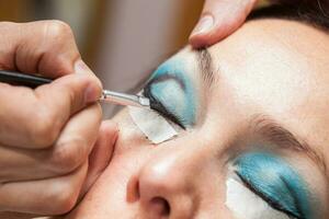 Make up artist creating cat eyes on a white woman photo