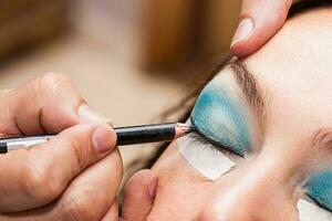 Make up artist using masking tape to create cat eyes photo