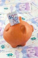 Saving Fifty Thousand Colombian Pesos Bills into a piggy bank.  Finance concept. Economy concept. Savings concept. photo