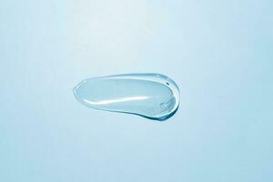 Squeezed cosmetic clear cream gel texture Iisolated on blue background. Close up transparent serum drop smear photo