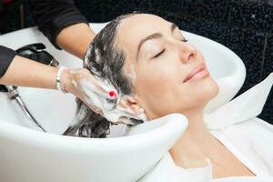blanco mujer consiguiendo un pelo lavar procedimiento en un belleza salón foto