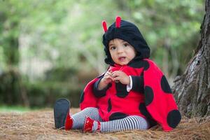 pequeño bebé niña vistiendo un mariquita traje. Víspera de Todos los Santos concepto. foto