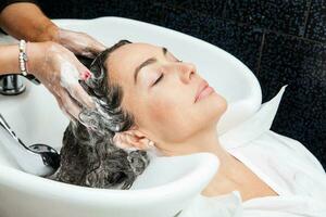 blanco mujer consiguiendo un pelo lavar procedimiento en un belleza salón foto