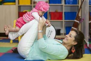 Beautiful young mother playing with her six months old baby indoors. Playing with Mom in the playroom photo