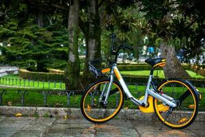 Yellow rental public bike parked at the Paseo del Prado on a rainy day in Madrid photo