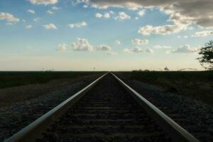 Railroad track converging at the horizon under the afternoon blue sky photo