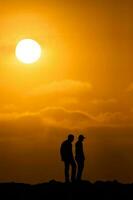 silueta de dos hombres a un hermosa naranja puesta de sol. tranquilidad concepto foto