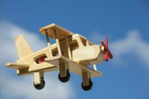 Wooden Plane flying with blue sky and white clouds - Side view photo