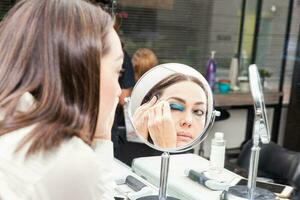 White woman removing makeup in front of mirror at beauty salon photo