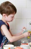 boy washing dishes in the sink in the kitchen photo