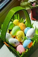 Easter green basket with plastic colored eggs on the windowsill photo