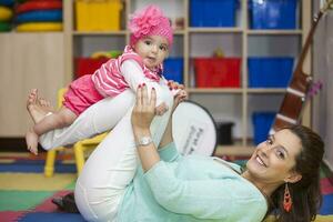 Beautiful young mother playing with her six months old baby indoors. Playing with Mom in the playroom photo