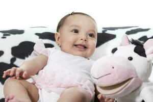 bebé niña jugando con su relleno juguete vaca foto