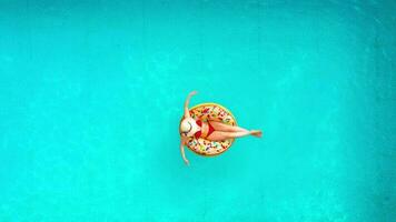 Aerial view of a woman in red bikini swimming on a donut in the pool video