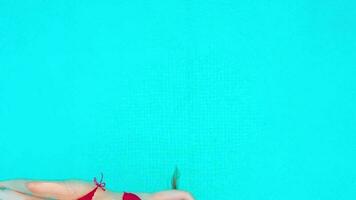 View from the top as a woman in red swimsuit lying on her back in the pool. Relaxing concept video