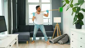 hombre limpieza el casa y teniendo divertido bailando con un escoba. lento movimiento video