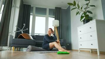 mujer se sienta en el medio de el habitación profundo en pensamiento. ella necesidades a limpiar arriba, pero ella procrastina video