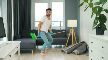 Mann Reinigung das Haus und haben Spaß Tanzen mit ein Besen. schleppend Bewegung video