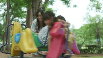 crianças sentar em uma carrossel dentro a Parque infantil junto. crianças jogando às ao ar livre Parque infantil dentro a parque em verão período de férias. saudável atividade. video