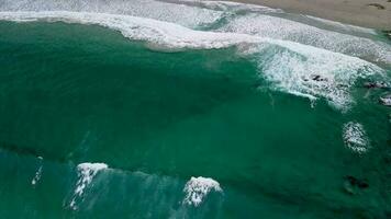 Antenne Schuss von Caion Strand groß Wellen kriechen sanft zu das Ufer während tagsüber im Koruna, Spanien. von oben nach unten video