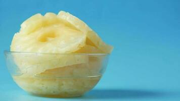 slice of pineapple in bowl on blue background video